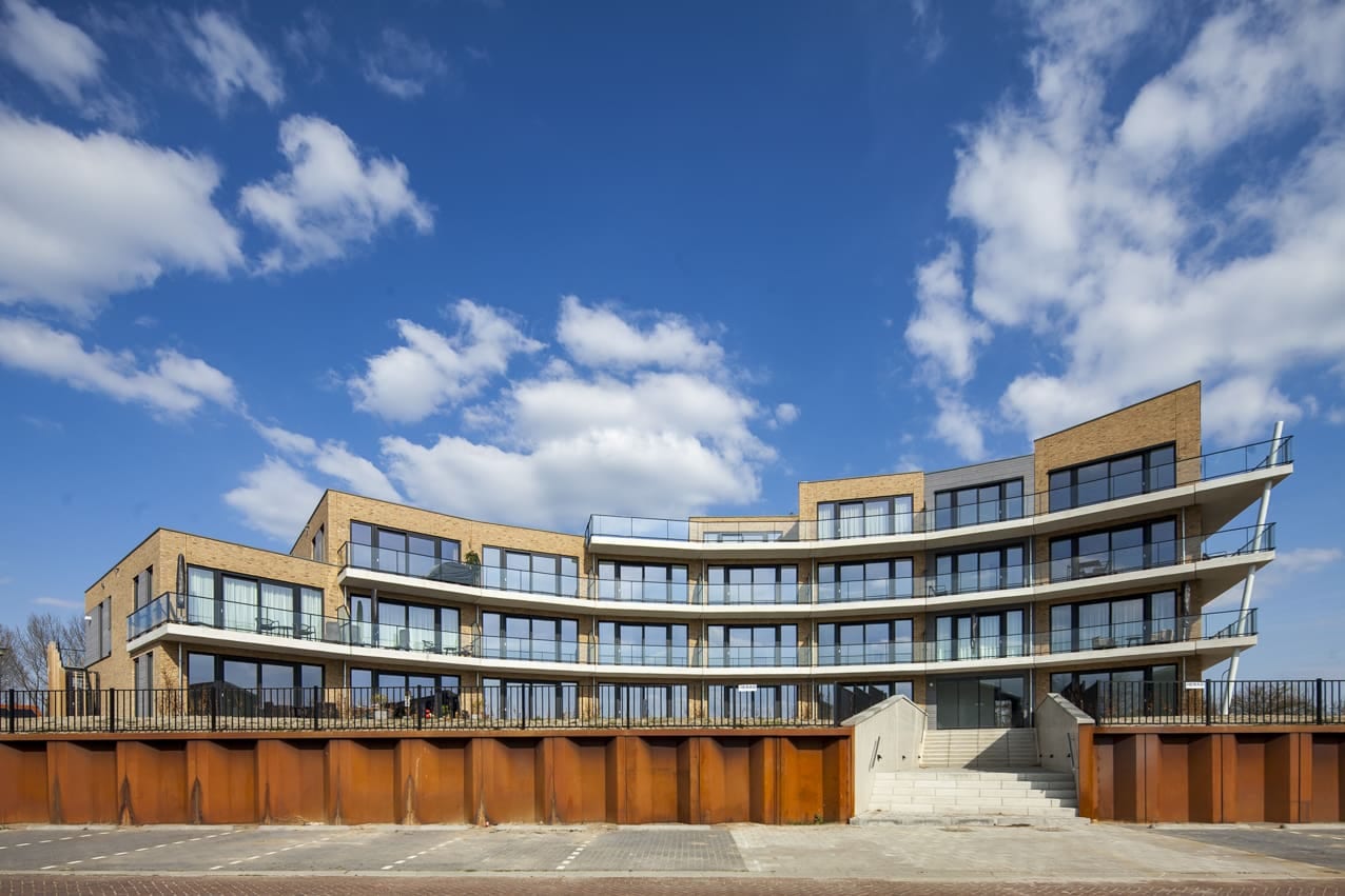 Het gebogen appartementengebouw Havenzicht in Kortgene met doorlopende balkonbanden, gezien vanaf de haven.
