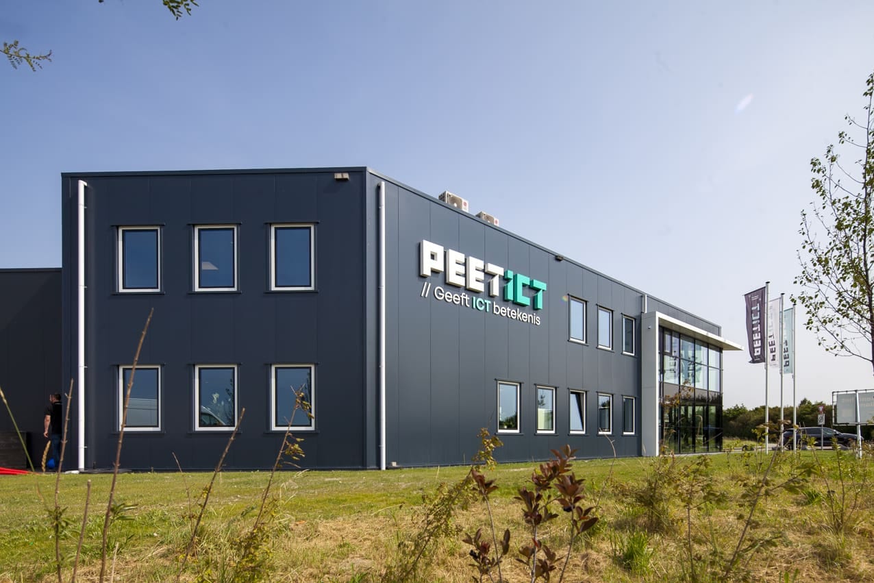 Het bedrijfspand van PEET ICT in Kamperland met donkergrijze gevelbekleding en glazen entree.